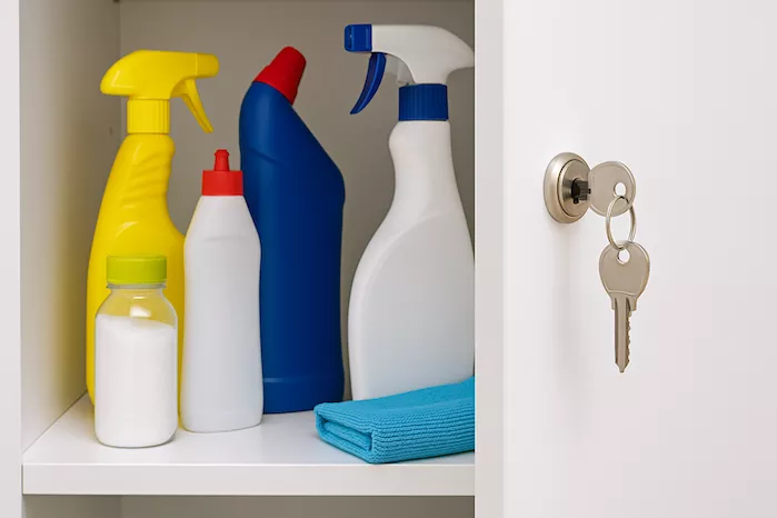 "Städprodukter förvaras säkert i låst skåp utom räckhåll för barn – symboliserar barnsäkerhet och ansvarsfull hantering av rengöringsmedel i hemmet"